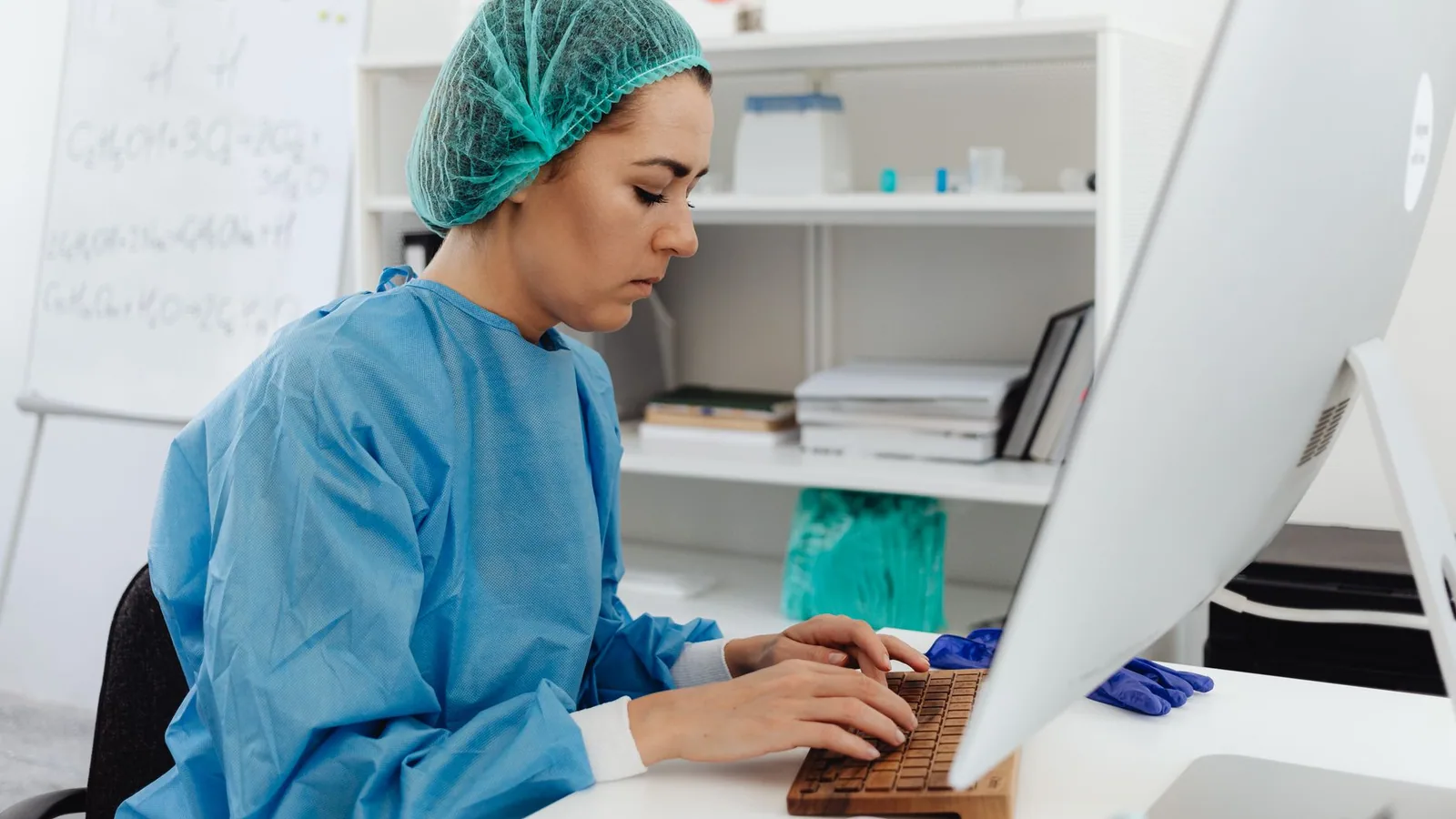 A female healthcare professional in scrub suit working on a computer in a laboratory setting