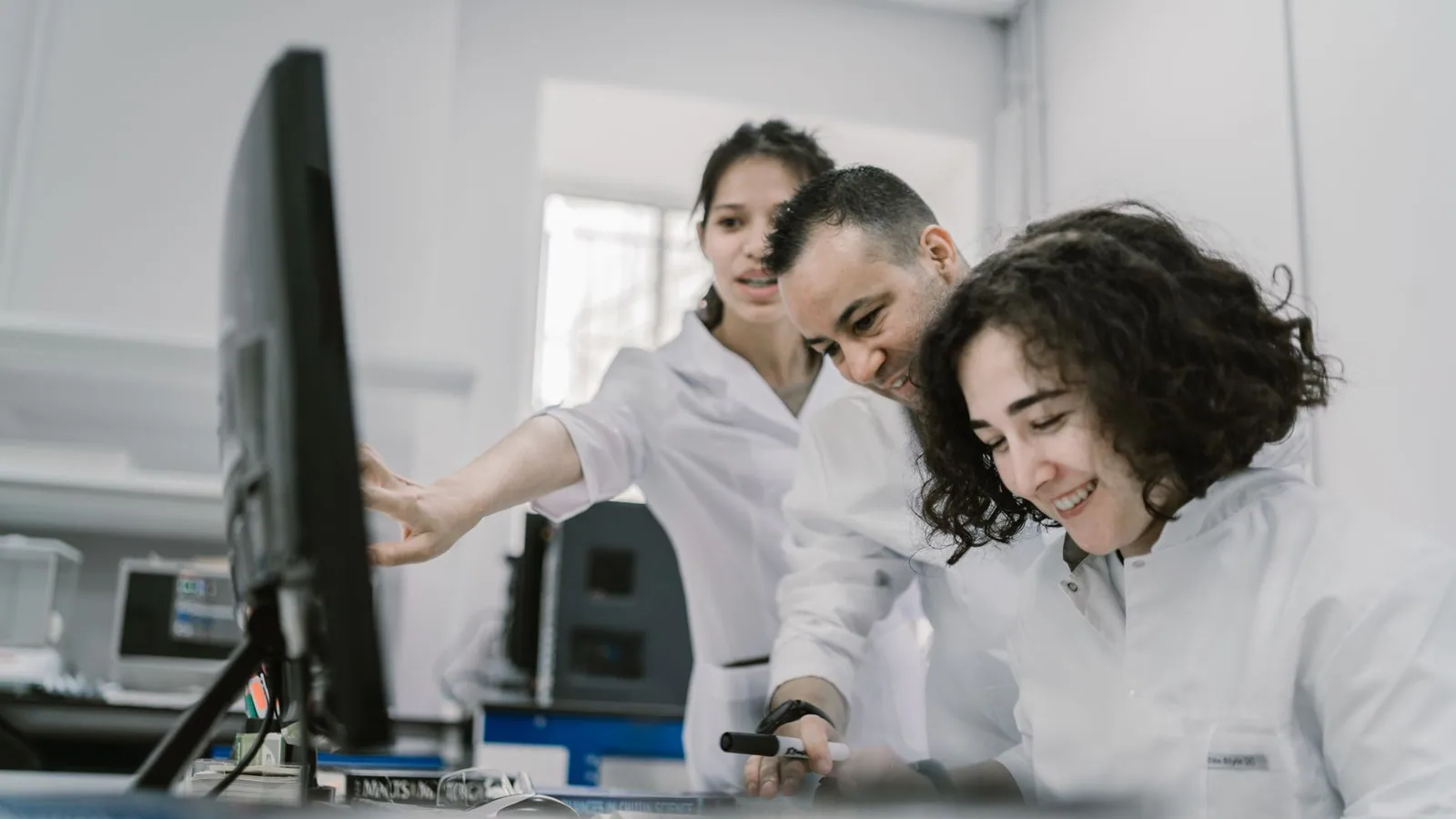 Group of diverse scientists working together on a computer in a bright, modern laboratory
