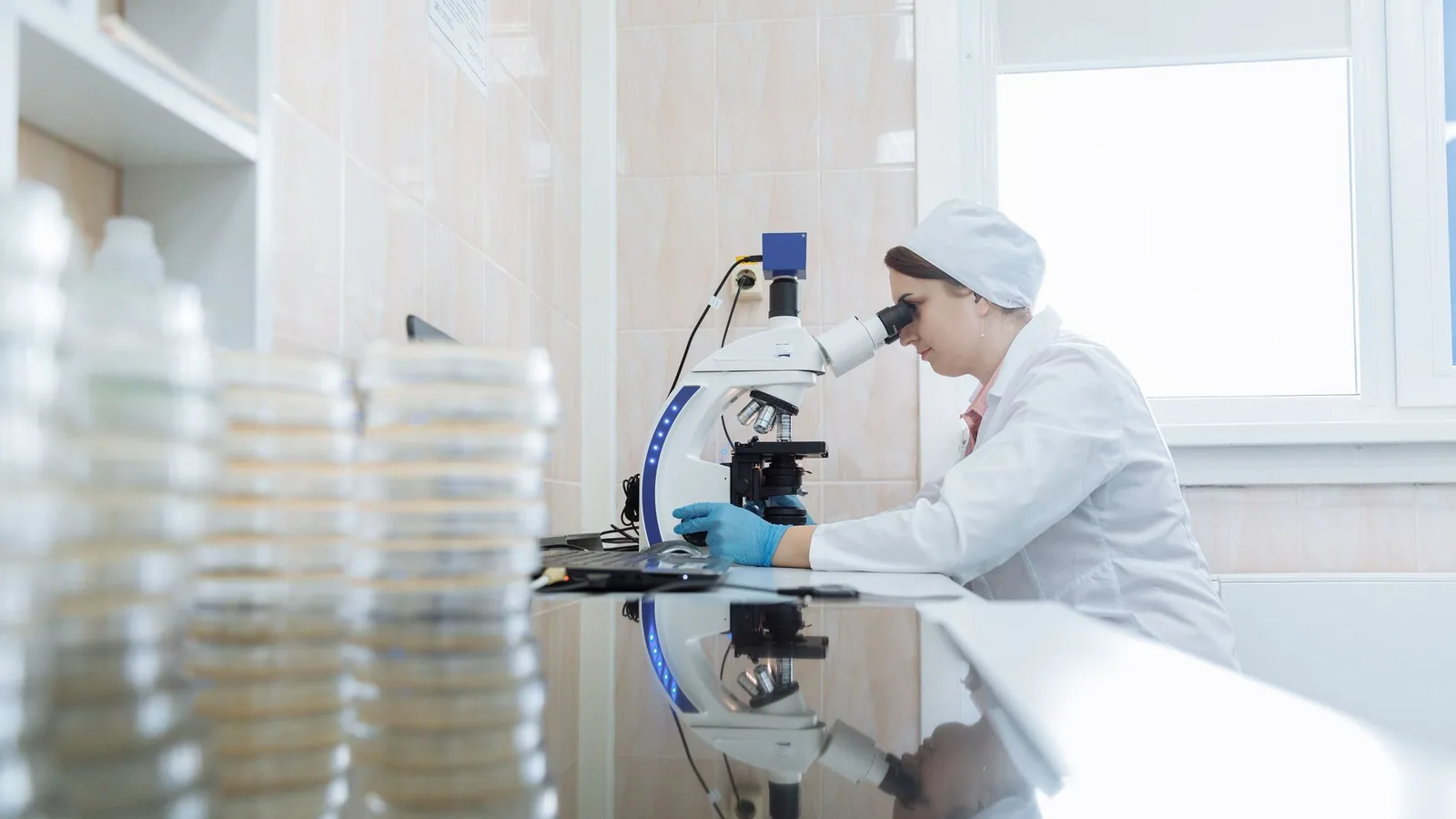 Female scientist using a microscope in a laboratory environment, focusing on research