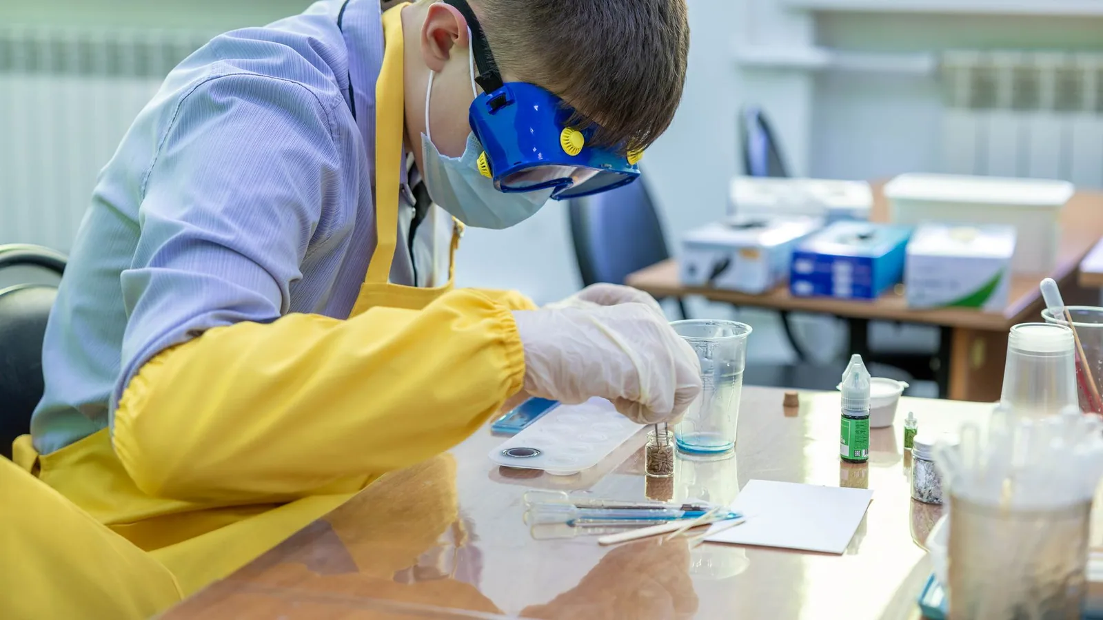 Young student in protective gear performing a chemistry experiment in a laboratory setting