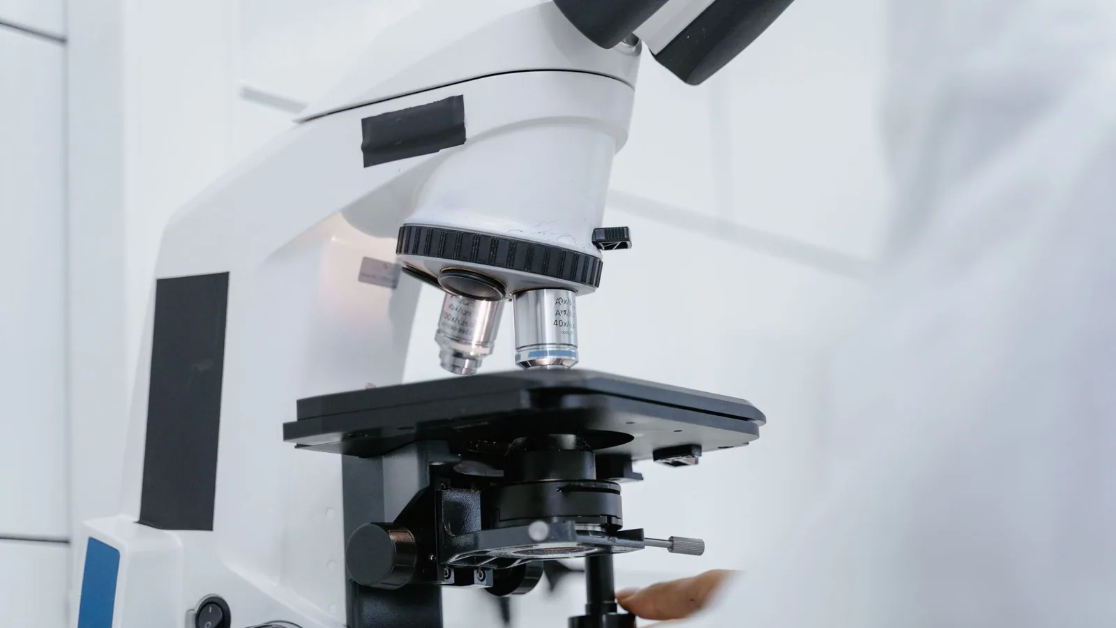 Detailed view of a scientist operating a microscope in a laboratory setting